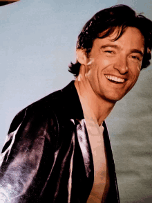 a man wearing a black leather jacket is smiling