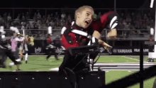 a man in a marching band uniform is standing on a field with a yamaha logo in the background .