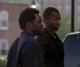 two men are standing next to each other in front of a window
