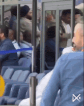 a group of people sitting in a stadium with an x on the bottom left