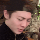 a close up of a man wearing a hat and earrings