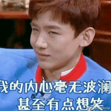 a young man wearing a blue shirt and a red collar is making a funny face in chinese .