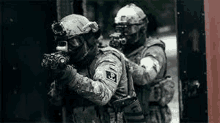 two soldiers are standing next to each other in a doorway holding guns .