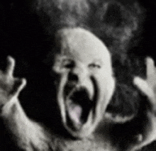 a black and white photo of a person screaming with their mouth wide open .