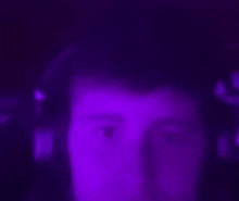 a blurry picture of a man 's face in a dark room with purple lights .