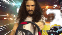 a man with long curly hair and a beard is driving a car with the words eurobeat behind him