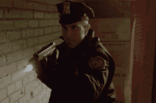 a police officer is holding a gun in front of a wall