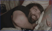 a man with a beard is laying on a bed with his head on a pillow