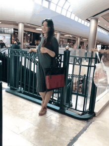 a woman in a green dress is standing next to a green railing