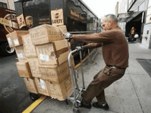 a delivery man is pushing a cart full of boxes on a sidewalk .