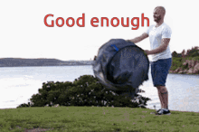 a man is standing on a grassy hill near a body of water with the words " good enough " written above him