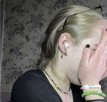 a woman covering her face with her hands and wearing earrings