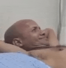 a bald man is laying in a hospital bed with his head on his arm .