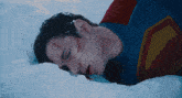 a man in a superman suit laying in the snow