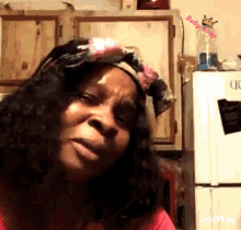 a woman wearing a headband with a crown on it is standing in front of a refrigerator in a kitchen