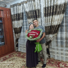 a man and a woman holding a bouquet of red roses with a message on the front that says " annatam umam "