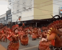 a group of people are dancing in a parade in front of a building with a sign that says ' a ' on it