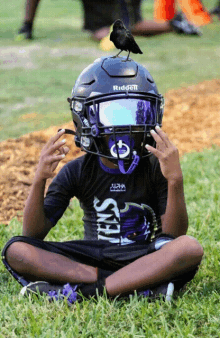 a young boy wearing a helmet that says riddell on it