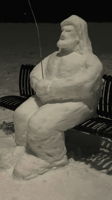 a statue of a man sitting on a bench holding a fishing rod