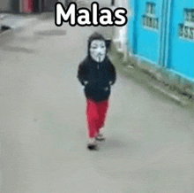 a young boy wearing a mask is walking down a street .