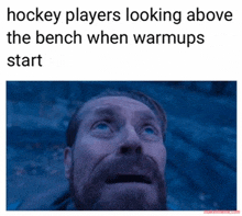 hockey players looking above the bench when warmups start with a picture of a man looking up