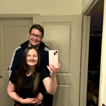 a man and woman taking a selfie in front of a door