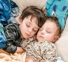 two young boys are sleeping next to each other in a bed