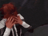 a man in a black and white suit holds his head with his hands