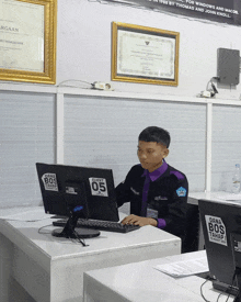 a man sits in front of a computer with a dana bos sticker on the screen