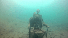 a skeleton sits in a chair underwater