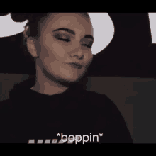 a woman is wearing a black hoodie and making a funny face while saying boppin .