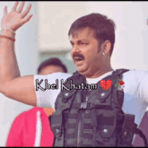 a man with a mustache is wearing a black vest with khel khatam on it