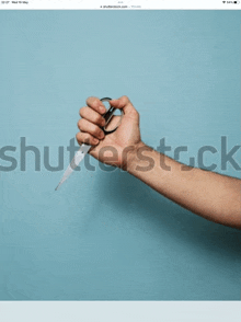 a person 's hand is holding a pair of scissors with a blue background