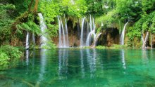 a waterfall in the middle of a lake with trees surrounding it