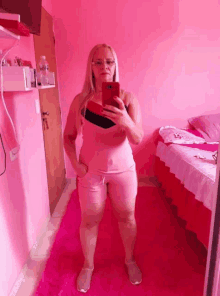 a woman taking a selfie in a pink room