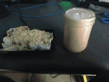 a jar of sauce sits on a table next to a tray of food