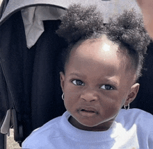 a little girl with curly hair is sitting in a stroller .