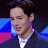 a young man in a suit and white shirt looks at the camera