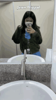 a woman taking a picture of herself in a bathroom mirror with the name jeon wigglel written above her