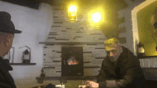 two men are sitting in front of a fireplace