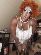 a drag queen wearing a white top and pearls