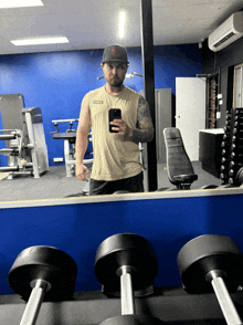 a man taking a picture of himself in a gym with a shirt that says ' army ' on it