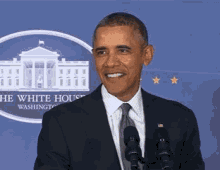 a man in a suit and tie is standing in front of two microphones in front of the white house in washington d.c.