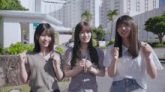 three girls are standing in front of a building with a sign that says ' ec ' on it
