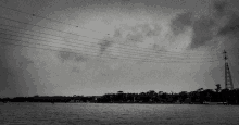 a black and white photo of a lake with a telephone pole in the foreground