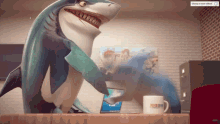 a cartoon shark is standing on a desk next to a cup that says bbc