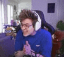 a man wearing headphones and glasses is sitting in a chair in front of a computer .