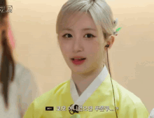 a young woman wearing a yellow kimono and headphones is talking to someone .