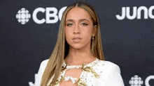 a woman is standing on a red carpet wearing a white dress and gold jewelry .