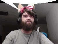 a man with a beard wears headphones and has a piece of paper on his head